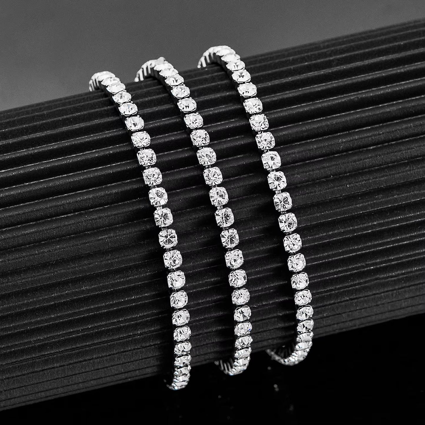 Aramat Jewels zilverkleurige stalen tennisarmband met fonkelende 4mm zirkonia stenen op een zwarte displayhouder.