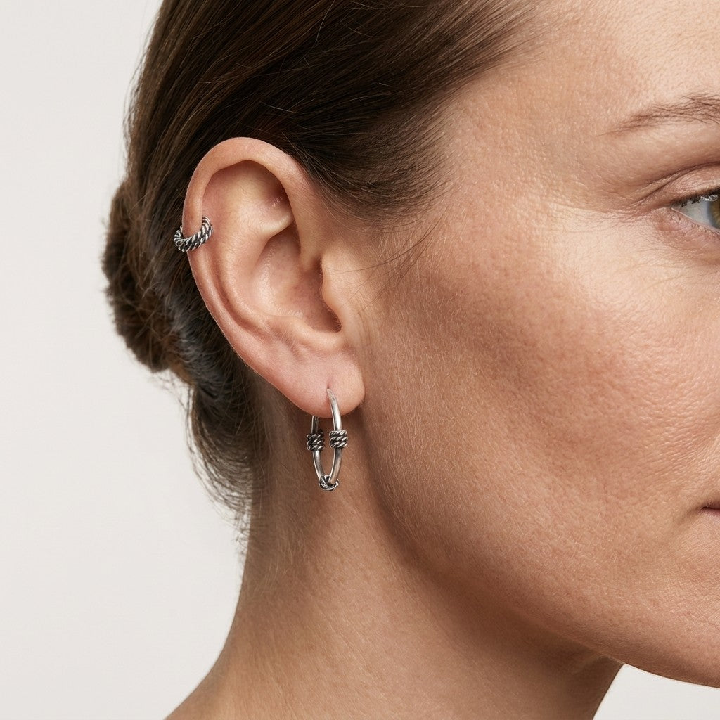 Aramat Jewels thin 16mm silver Bali hoop earrings with a subtle knot detail. A matching ear cuff is worn on the upper ear.