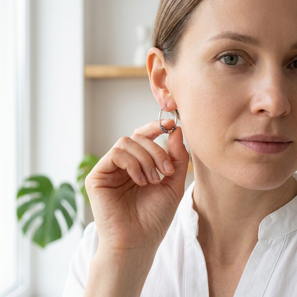 Aramat Jewels thin 16mm silver Bali hoop earrings with intricate detailing, worn by a woman.