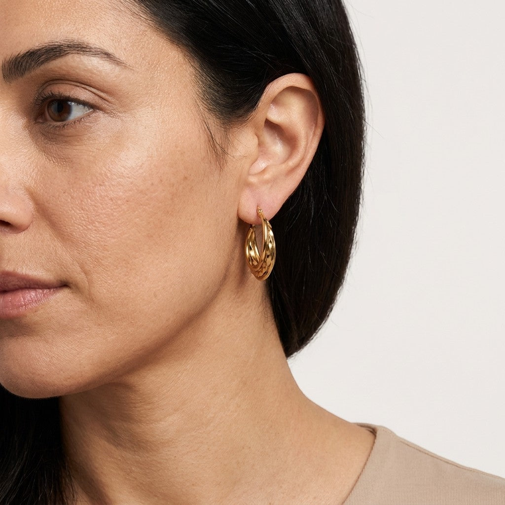 Aramat Jewels triple gold hoop earrings, 30x7.5mm, featuring two smooth rings and one twisted ring. Worn by a woman.