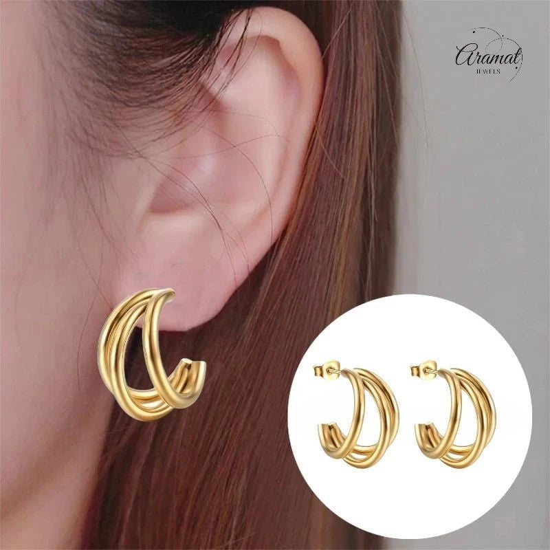Aramat Jewels goudkleurige triple halve oorringen van roestvrij staal, gedragen in het oor voor een trendy look.