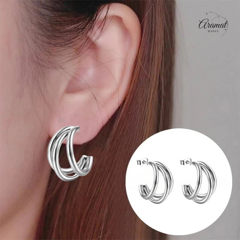 Aramat Jewels zilverkleurige triple halve oorringen van roestvrij staal, gedragen in een oor voor een stijlvolle look.