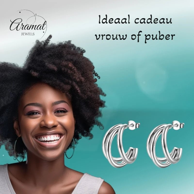 Lachende vrouw draagt zilverkleurige triple halve oorringen van Aramat Jewels, gemaakt van roestvrij staal.