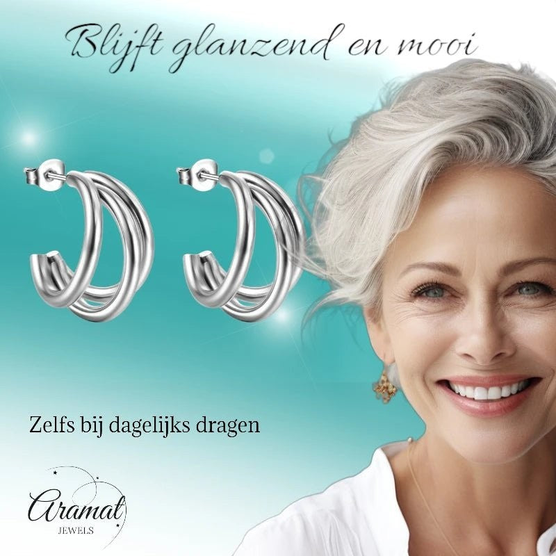 Aramat Jewels zilverkleurige triple halve oorringen van roestvrij staal, gedragen door een stralende vrouw.