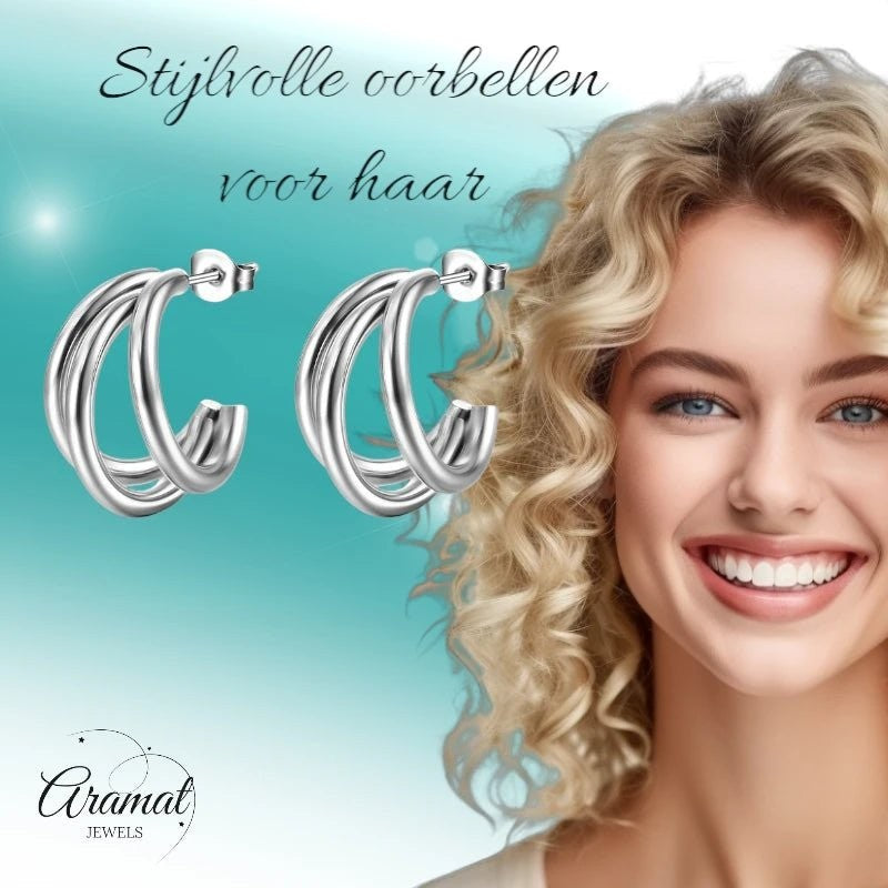 Aramat Jewels zilverkleurige triple halve oorringen van roestvrij staal met vlindersluiting, gedragen door een model.