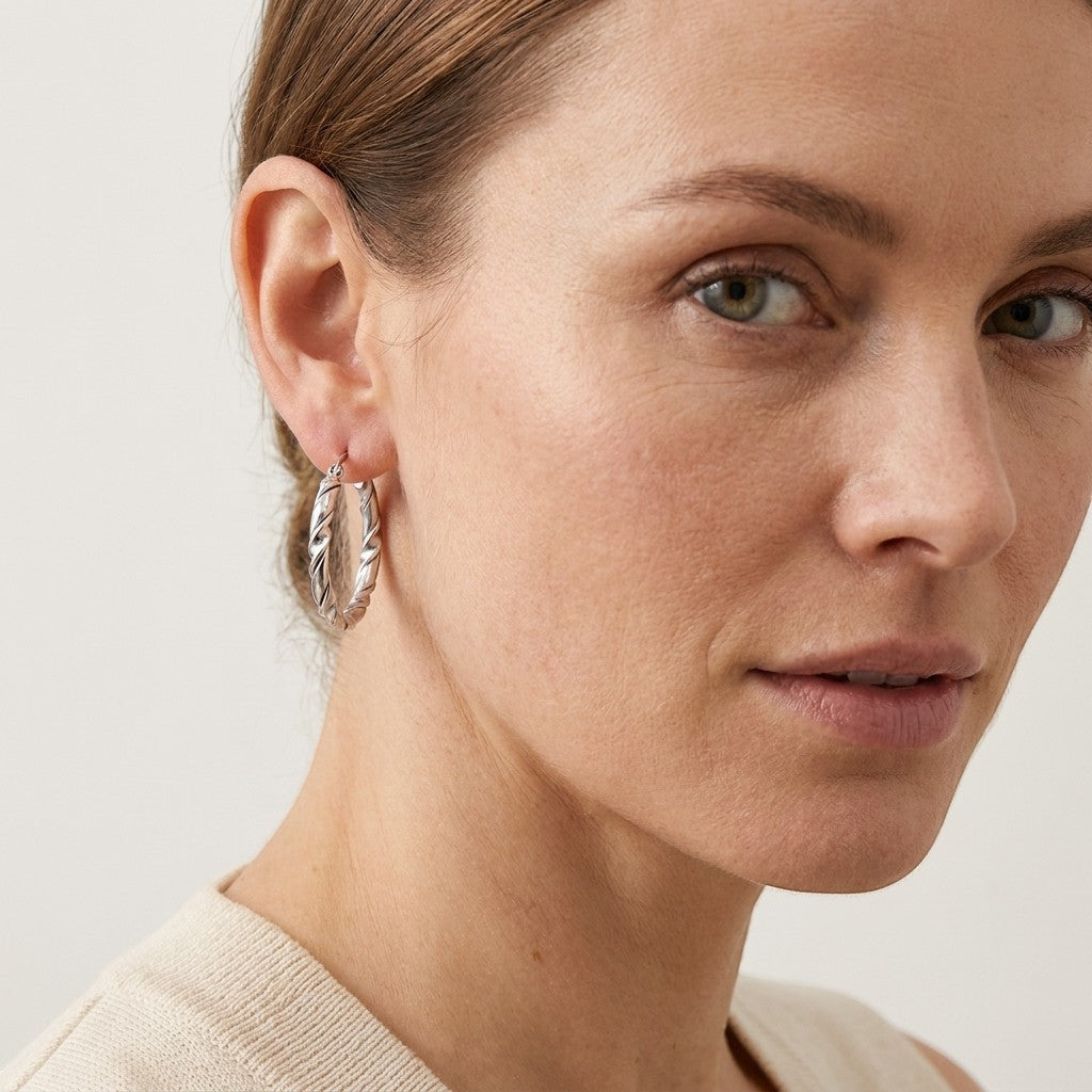 Aramat Jewels silver-tone stainless steel twisted hoop earrings, 30mm diameter, featuring a two-strand design with one smooth and one curved strand.