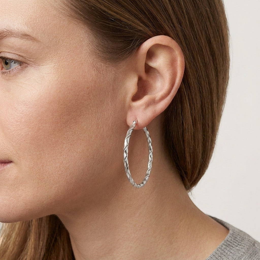 Aramat Jewels silver-tone twisted hoop earrings, 45mm, made of stainless steel, worn by a woman.