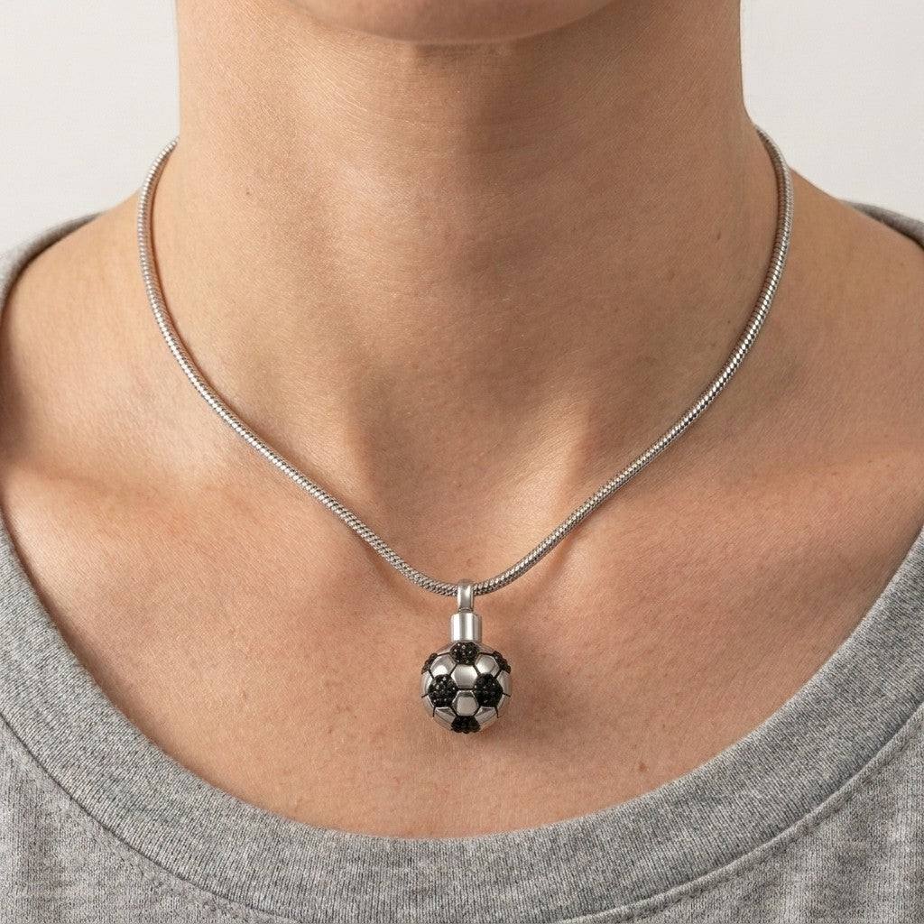 Aramat Jewels zilverkleurige RVS voetbal ashanger met zwarte details, gedragen door een vrouw.