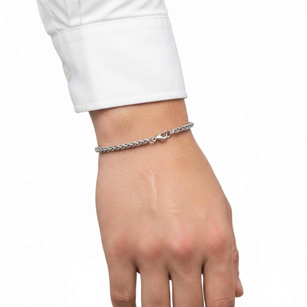 Aramat Jewels zilverkleurige vossenstaart armband van RVS met gevlochten schakels om een pols met wit overhemd.