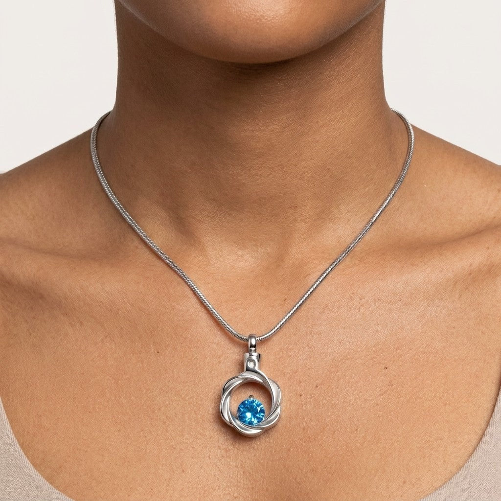 Aramat Jewels zilverkleurige stalen ashanger met blauwe zirkonia, gedragen aan een slangenketting.