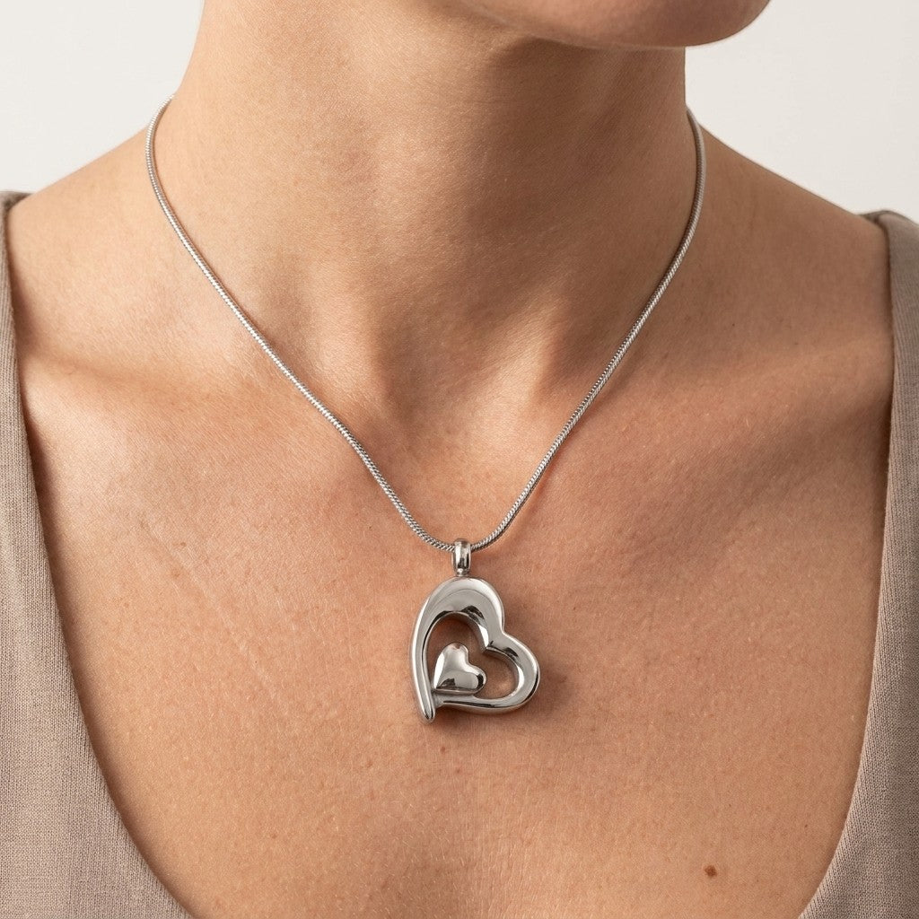 Aramat Jewels zilverkleurige dubbele hart ashanger van roestvrij staal, gedragen door een vrouw.