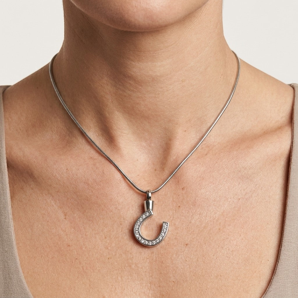 Aramat Jewels zilverkleurige stalen hoefijzer ashanger met steentjes, gedragen door een vrouw.