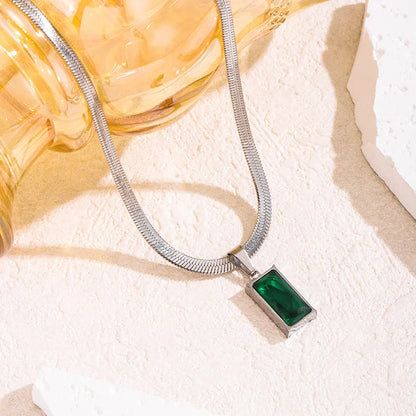 Aramat Jewels zilverkleurige platte slangenketting met een rechthoekige groene zirkonia hanger op een lichte ondergrond.