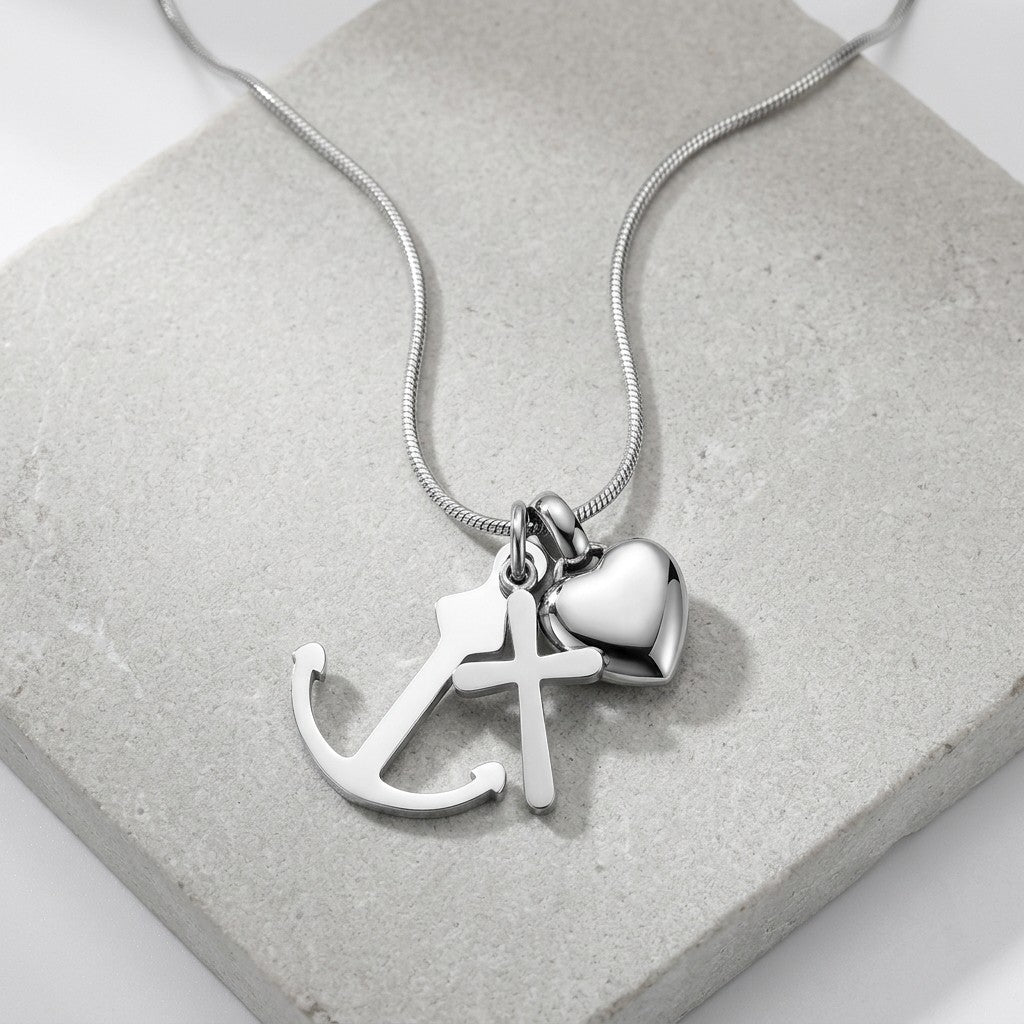 Aramat Jewels zilverkleurige ashanger met kruis, anker en hart symbool, gemaakt van RVS.