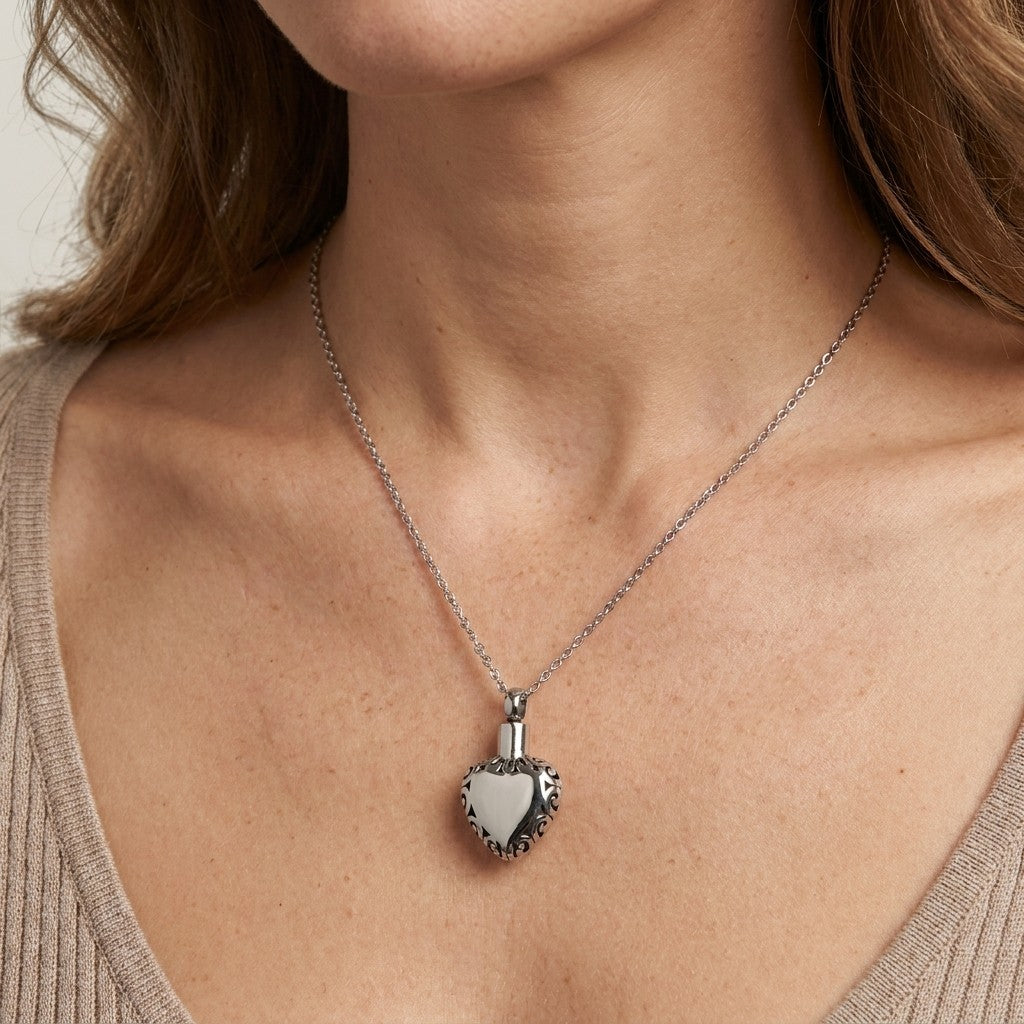 Aramat Jewels zilverkleurige hartvormige ashanger met sierlijke rand, gemaakt van roestvrij staal.