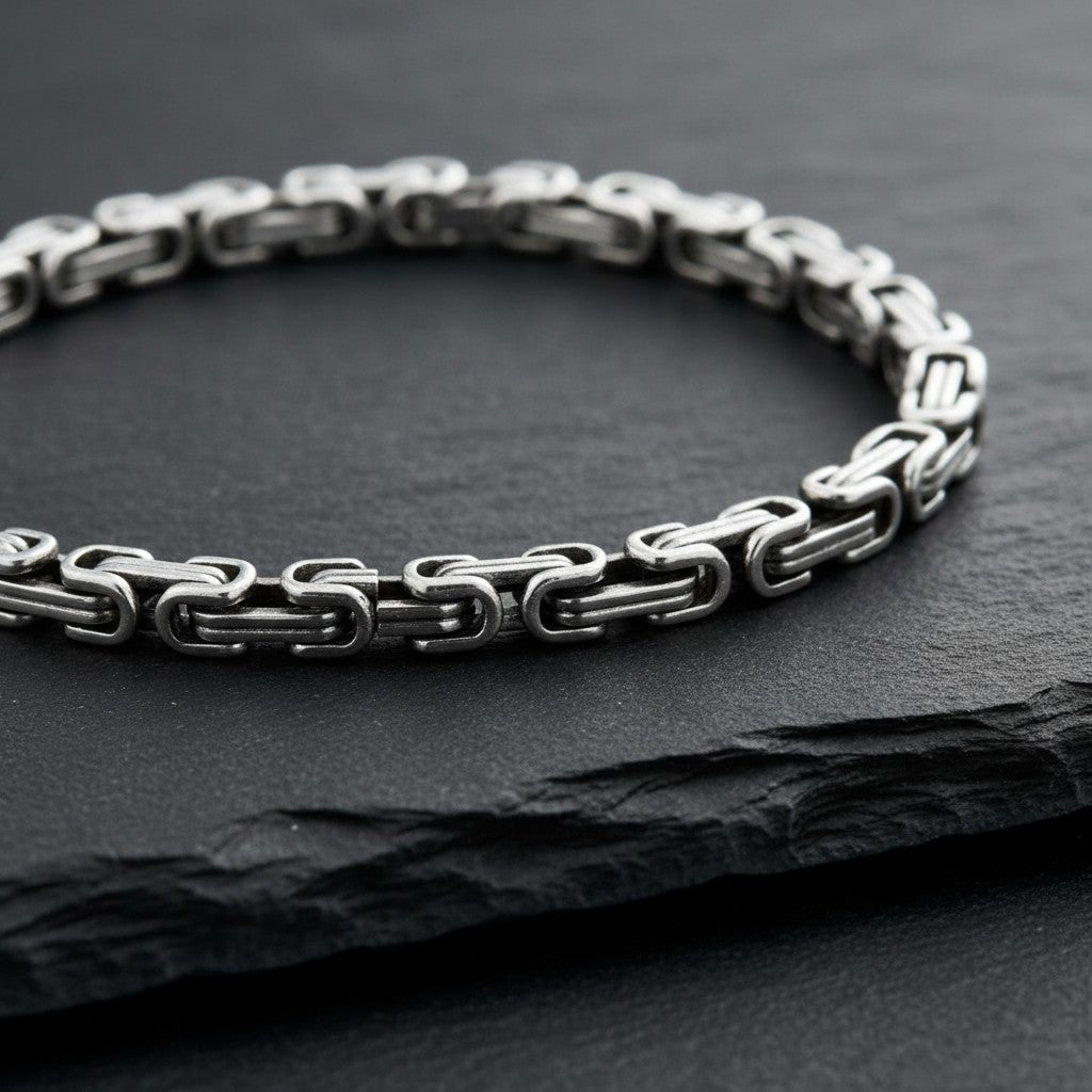 Aramat Jewels zilverkleurige RVS koningsschakel armband van 5mm breed en 20cm lang op een zwarte leistenen ondergrond.