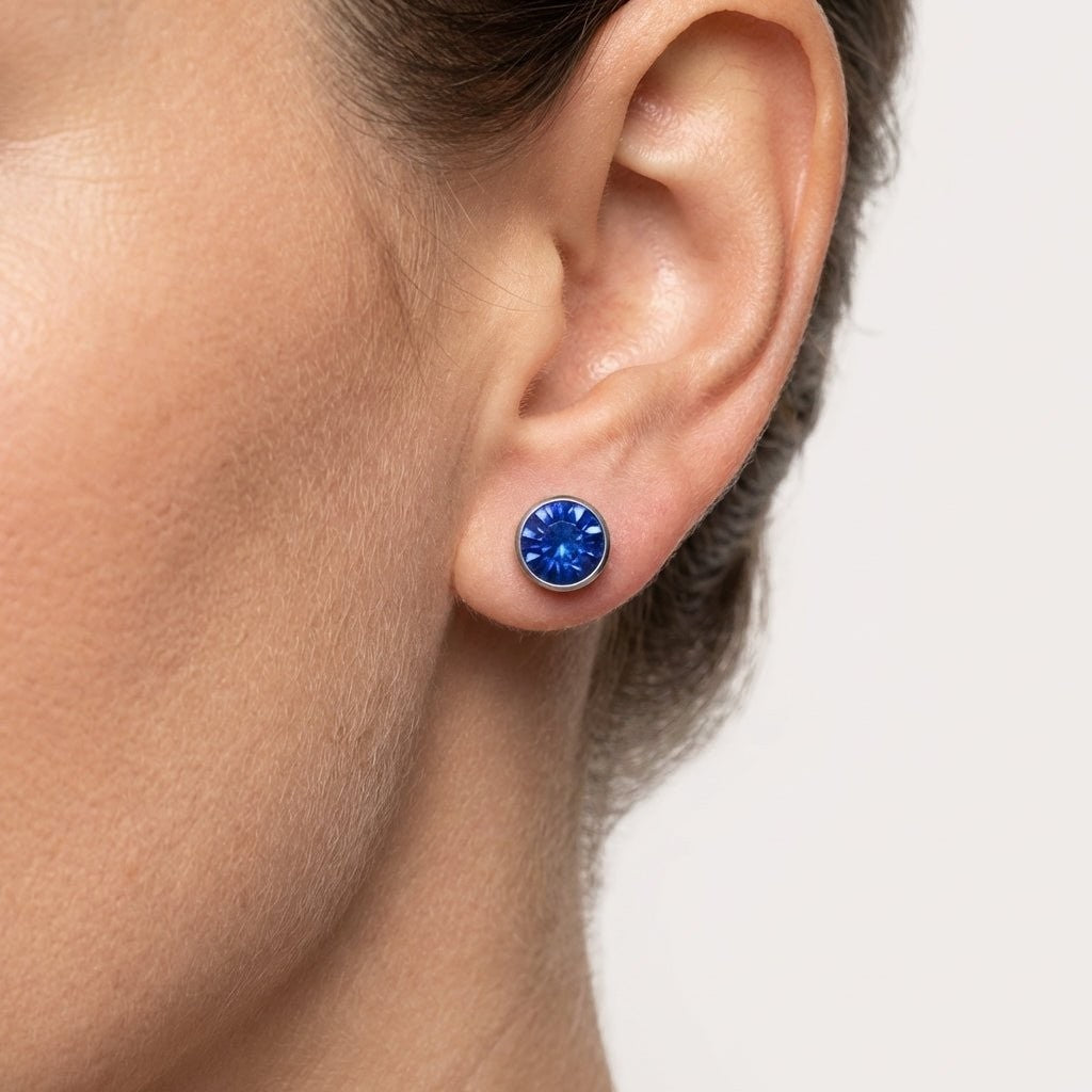 Aramat Jewels zilverkleurige oorstekers met een 7mm donkerblauw kristal, gemaakt van roestvrij staal.