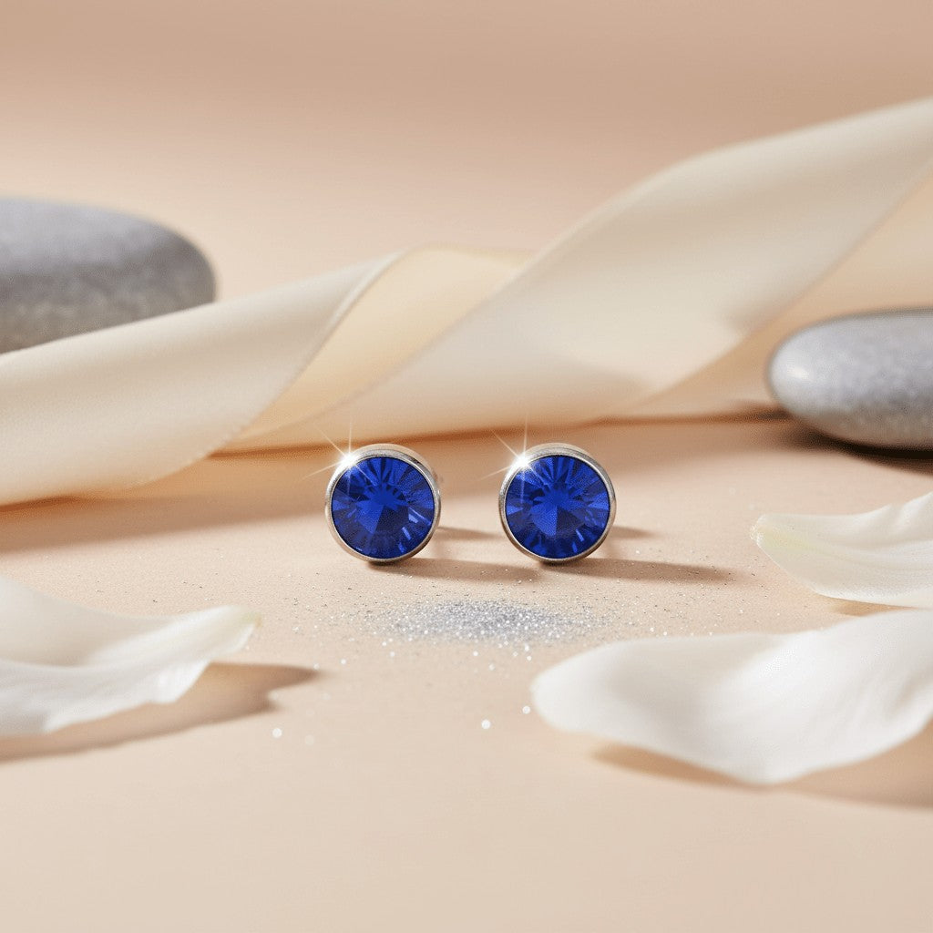 Aramat Jewels zilverkleurige oorstekers met donkerblauwe kristallen van 7mm, gemaakt van roestvrij staal.