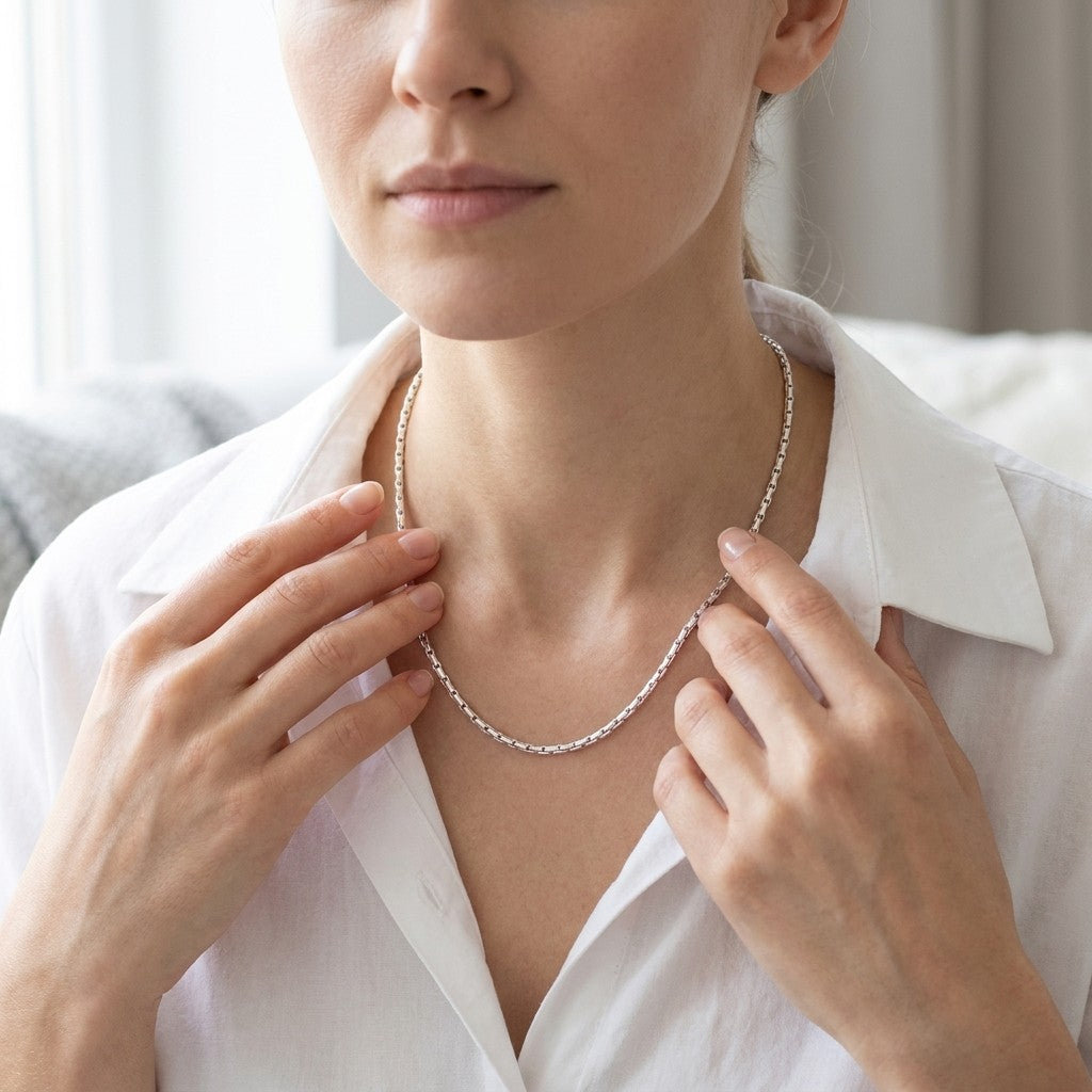 Aramat Jewels zilverkleurige slangenketting van roestvrij staal gedragen door een vrouw in een wit overhemd.