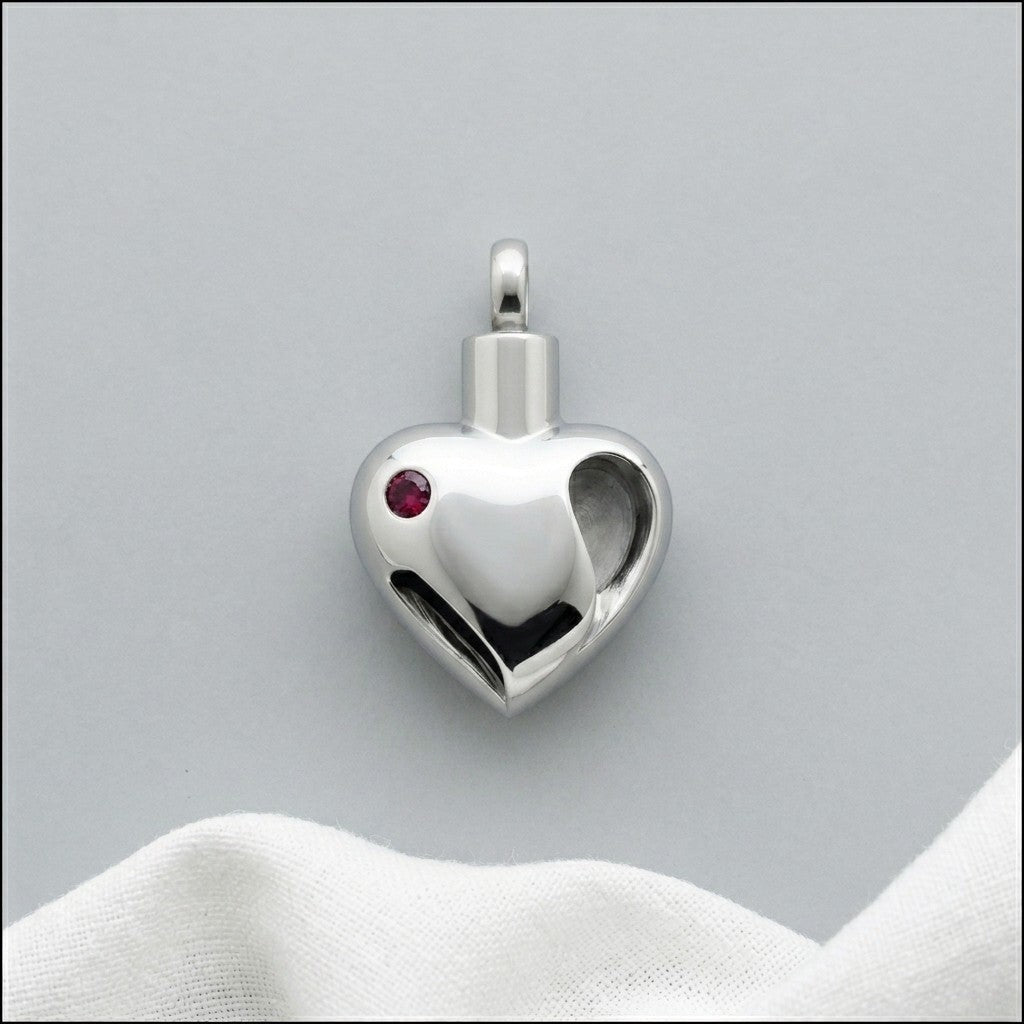 Aramat Jewels zilverkleurige stalen ashanger in hartvorm met rode zirkonia, waterbestendig.