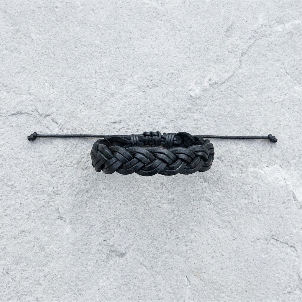 Aramat Jewels zwarte gevlochten leren armband van 16mm breed met een verstelbare sluiting op een grijze ondergrond.
