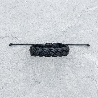 Aramat Jewels zwarte gevlochten leren armband van 16mm breed met een verstelbare sluiting op een grijze ondergrond.