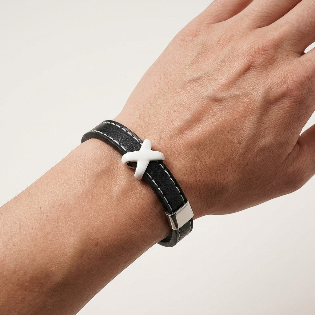 Aramat Jewels zwarte leren herenarmband met wit stiksel en een opvallend kruisje om de pols.