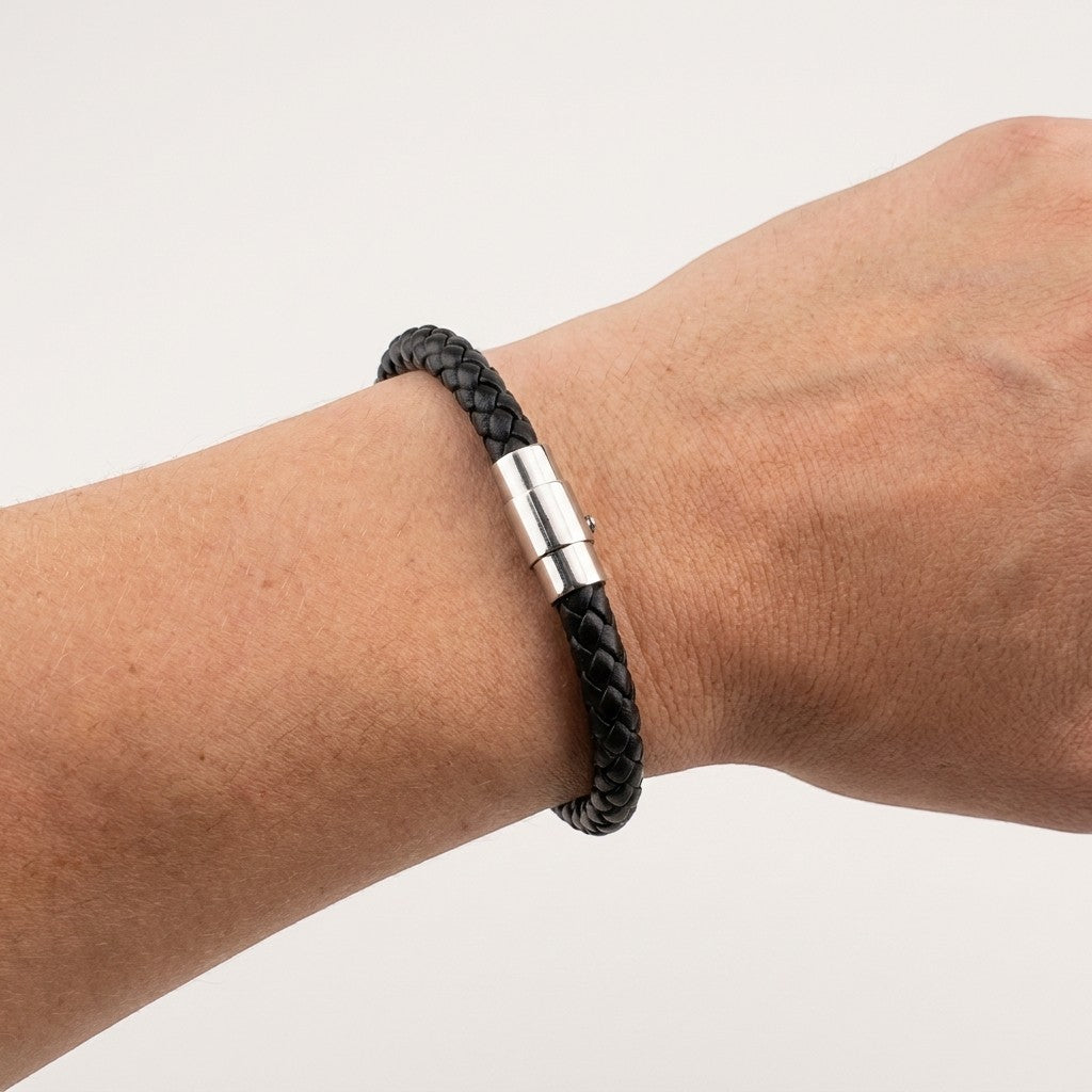 Aramat Jewels zwarte gevlochten leren armband met zilverkleurige RVS magneetsluiting om een pols.
