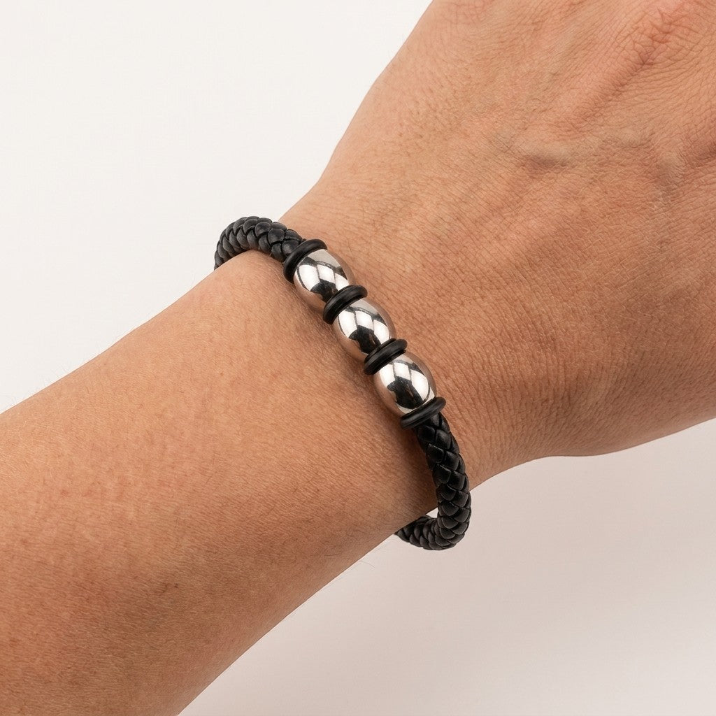 Aramat Jewels stoere zwarte gevlochten leren herenarmband met drie zilverkleurige stalen kralen om een pols.