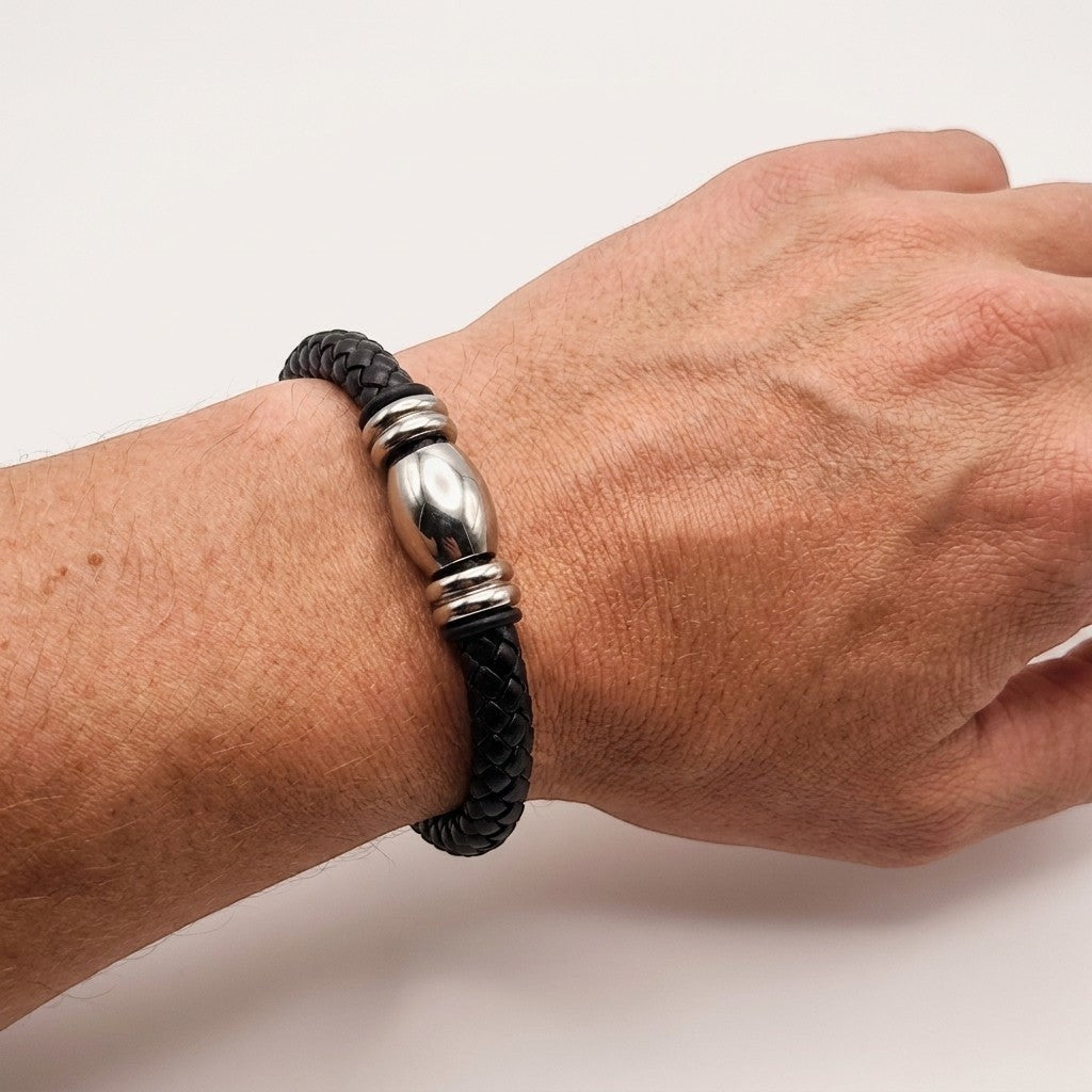 Aramat Jewels stoere zwarte gevlochten leren herenarmband met zilverkleurige stalen kralen om een pols.