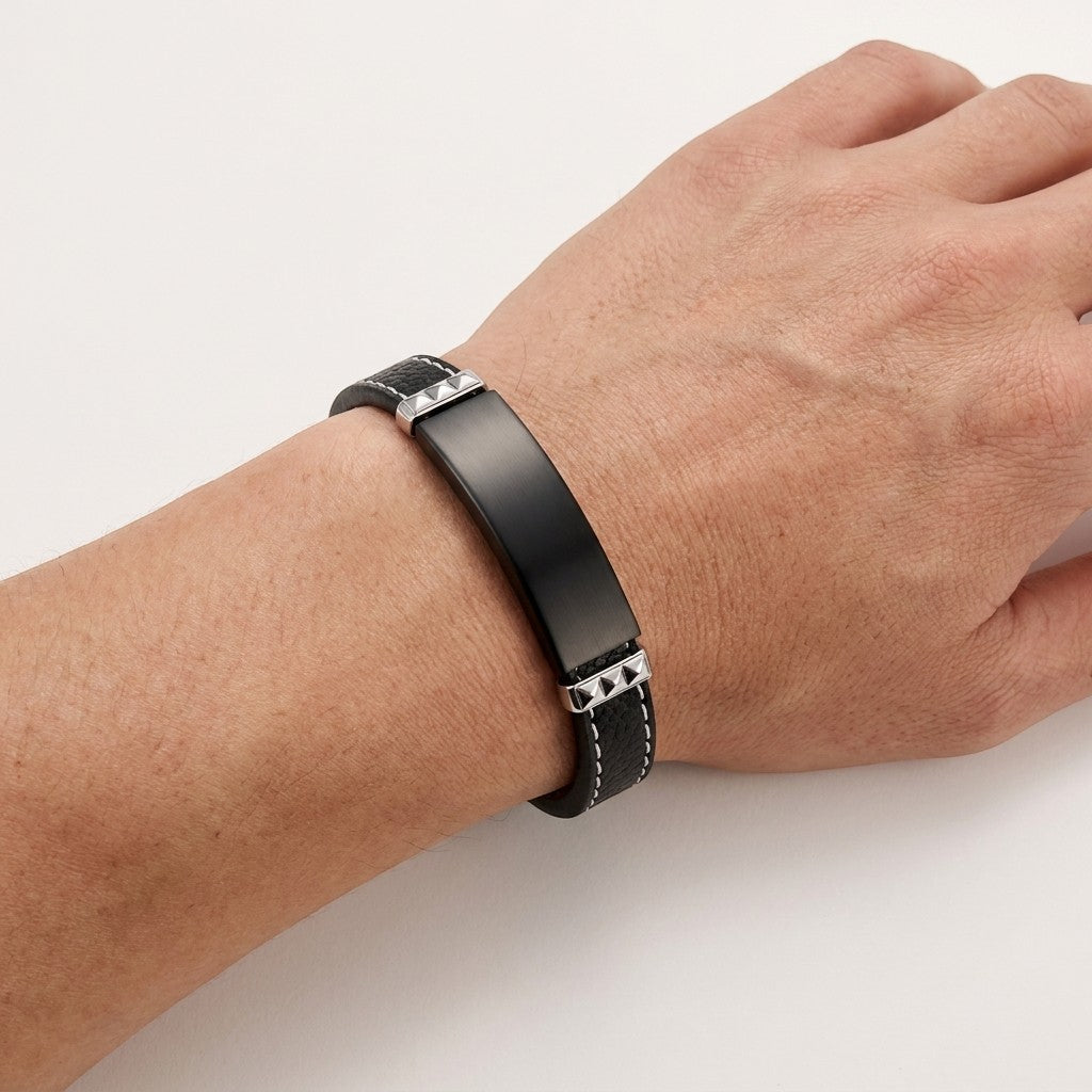 Aramat Jewels zwarte leren herenarmband met graveerbare zwarte stalen plaat, wit stiksel en 316L RVS details.