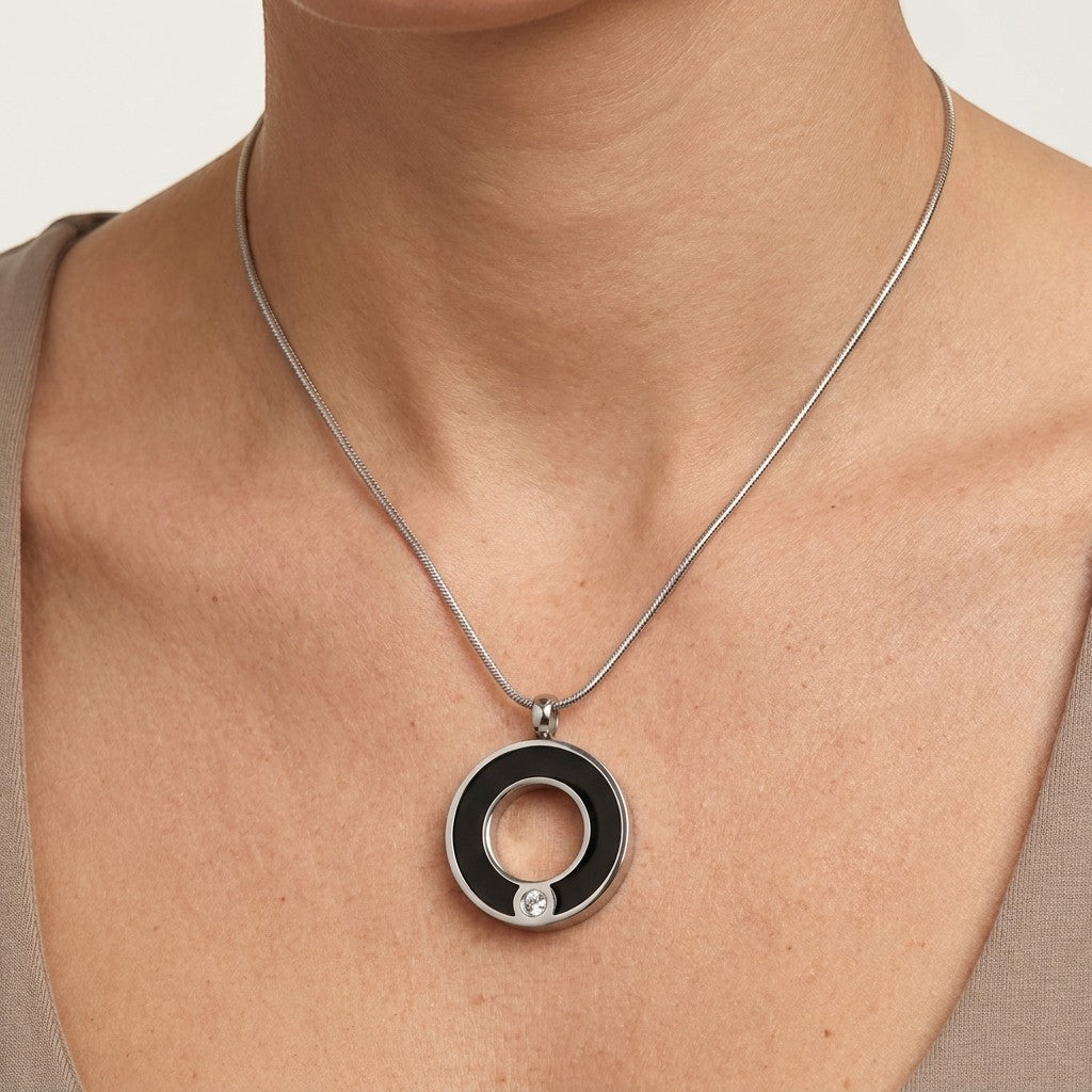 Aramat Jewels zwarte ronde stalen ashanger met een klein kristal, zonder ketting.