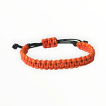 Een armband met oranje kralen en zwart koord