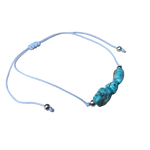 Een blauwe armband met een wit koord en een turquoise bea