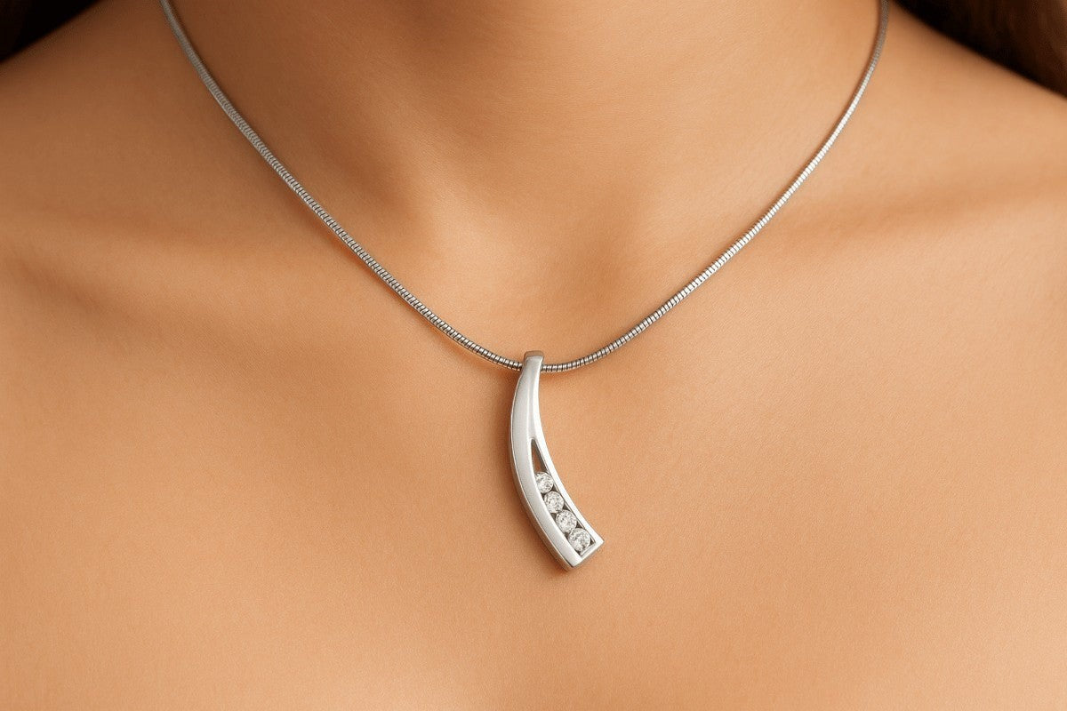 Zilveren gebogen ashanger met diamanten inleg, 33x7mm, met elegante curve en rij briljante diamanten zichtbaar door de uitgesneden binnenkant, gedragen op vrouwenhals met zilveren slangenketting.
