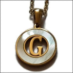 Een gouden en witte hanger met een letter g