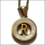 Een gouden en witte hanger met de letter r in het midden