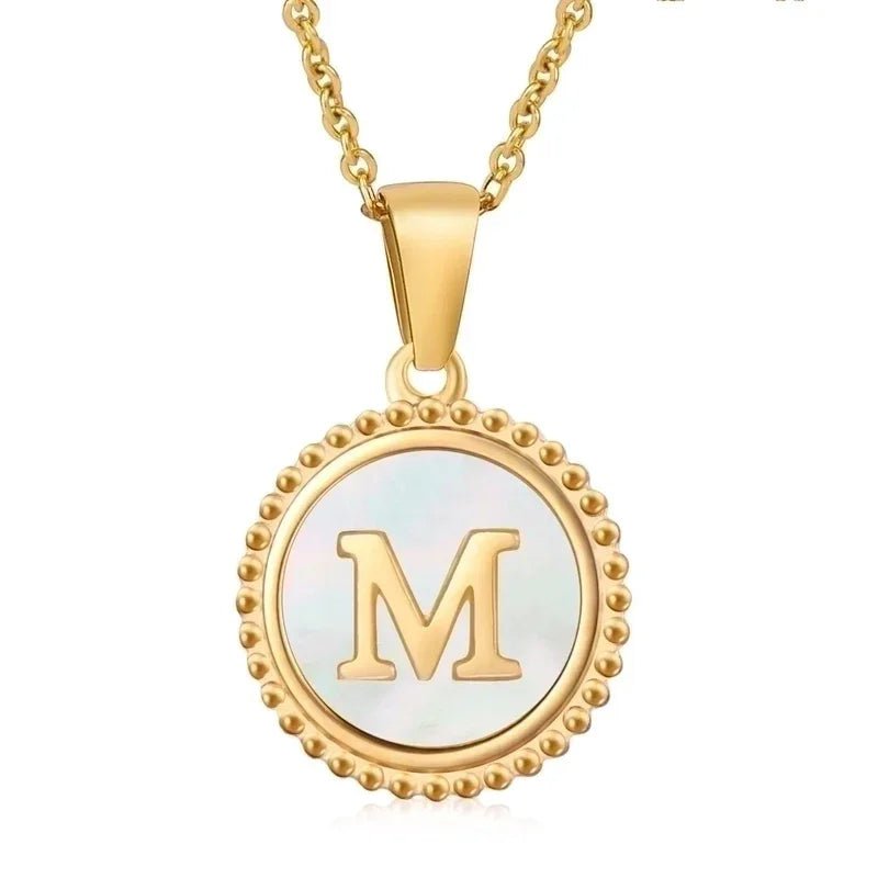 Hanger met vergulde ketting met de letter ’M’ op een parelmoeren schijf met kralenrand.