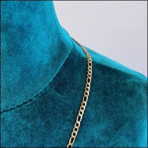 Een close-up van een gouden ketting op een blauwe fluwelen jurk