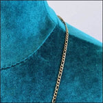 Een close-up van een blauw shirt met een gouden ketting eraan