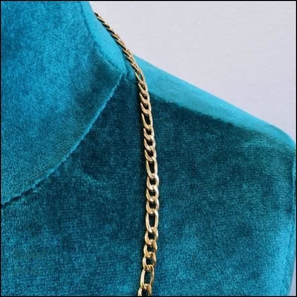 Een close-up van een gouden ketting op een blauwe fluwelen jurk