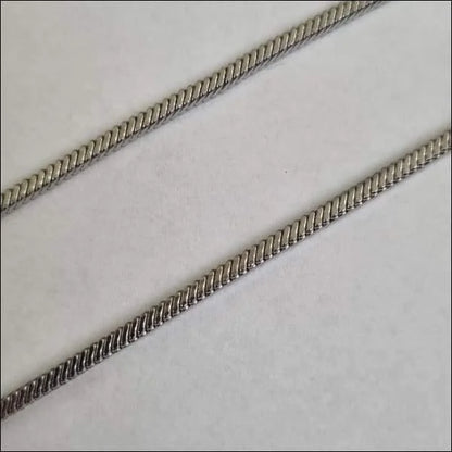 Twee Zilveren Kettingen Op Een Wit Oppervlak - Stalen Vierkante Slangenketting