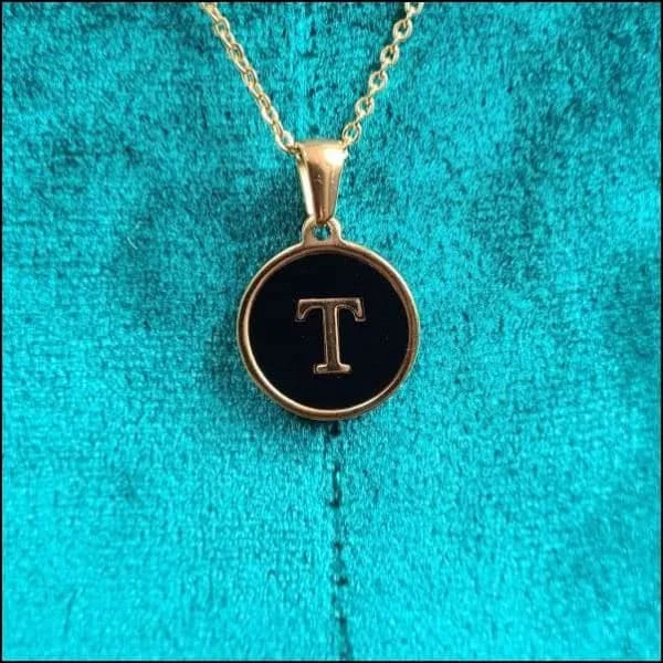 Een gouden ketting met een zwarte letter t erop