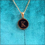 Een gouden ketting met een zwarte letter k erop