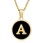 Hanger met vergulde ketting met de letter ’A’ op een zwarte ronde achtergrond.