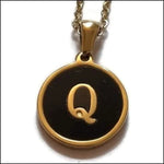 Een gouden en zwarte hanger met de letter q