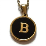 Een zwart met gouden hanger met de letter b