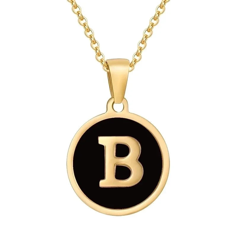 Gouden hangerketting met de letter ’B’ op een zwarte ronde achtergrond.