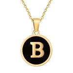 Gouden hangerketting met de letter ’B’ op een zwarte ronde achtergrond.