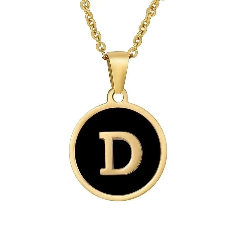 Hanger met vergulde ketting met de letter ’D’ op een zwarte ronde achtergrond.